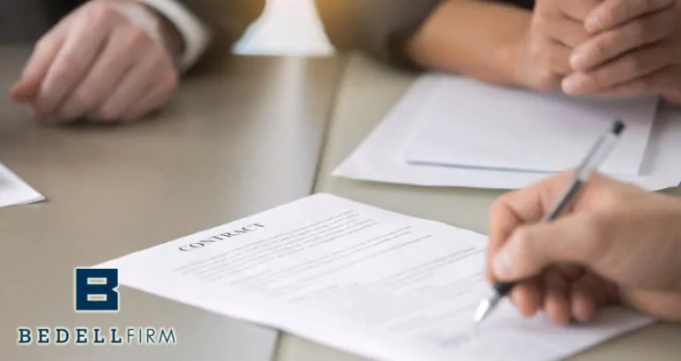 Three professionals' hands placed on a desk. One hand is holding a pen and writing on a contract