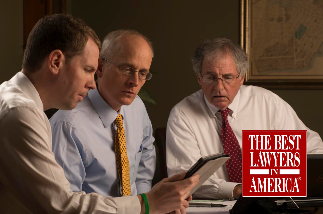 Brian Coughlin, David Barksdale, and Hank Coxe sitting around a conference table looking at a document together