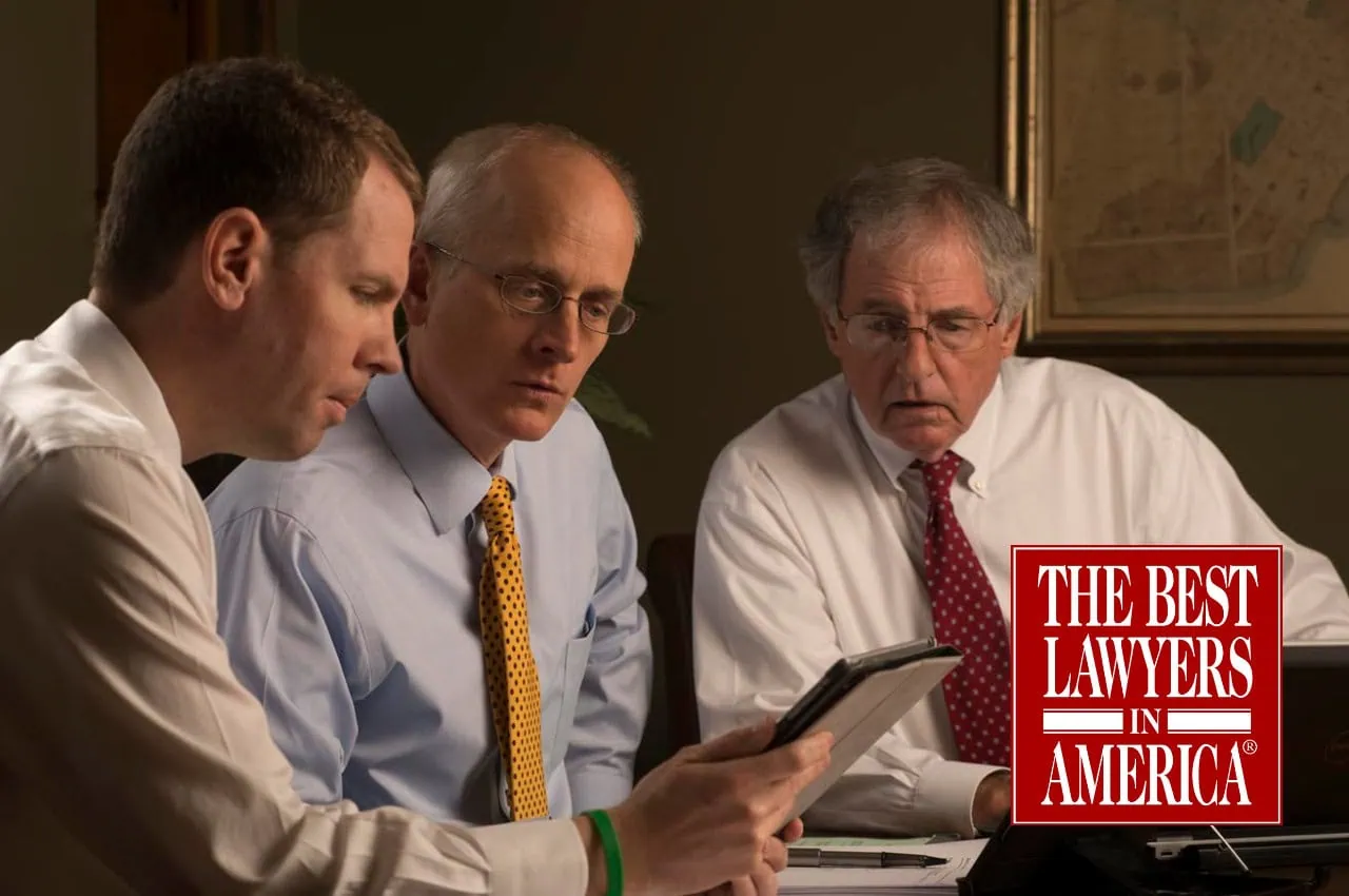 Brian Coughlin, David Barksdale, and Hank Coxe sitting around a conference table looking at a document together