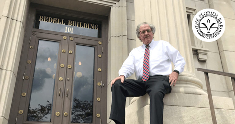 Hank Coxe sits against a podium outside of the Bedell Firm's building